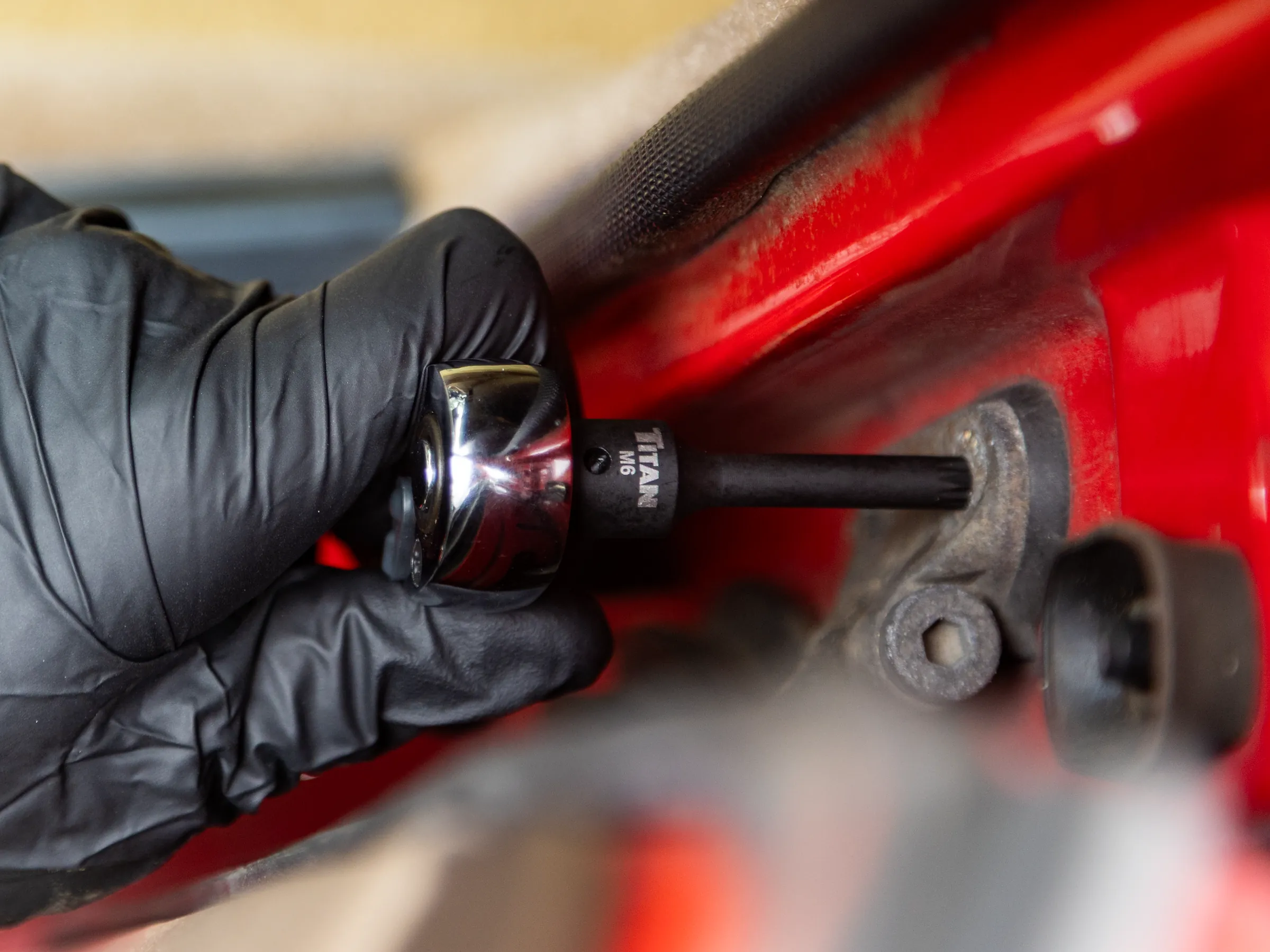 Gloved hand driving a Titan M6 bit socket on a ratchet